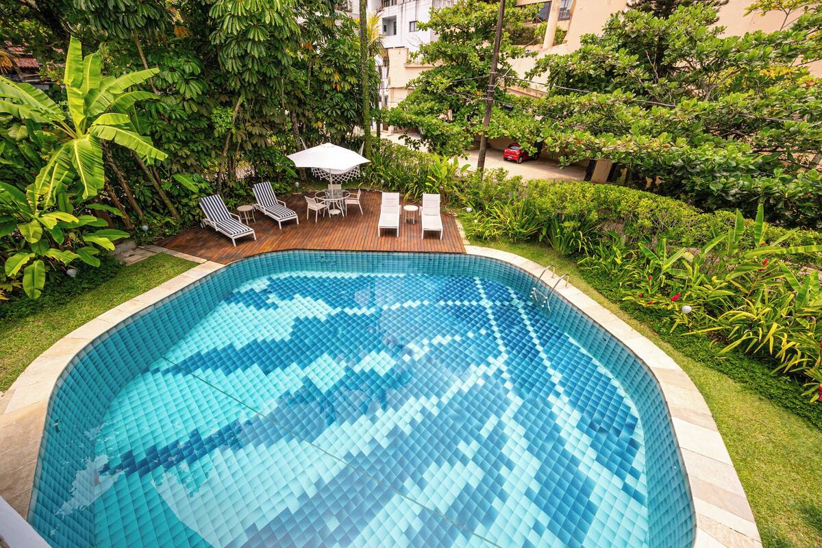 Une piscine dotée d’une terrasse carrelée, entourée d’une végétation luxuriante et agrémentée d’une petite table avec des chaises.