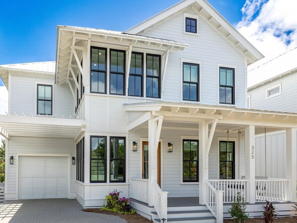 A two-story white house with a covered porch, large windows, and a garage. - Honeybee | Elegant 30A Retreat, 6 Bikes +Community Pool (Santa Rosa Beach)