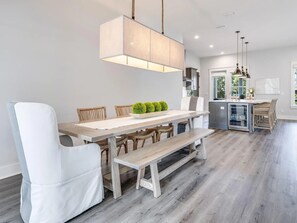 A modern kitchen with a central island, wooden flooring, and pendant lighting. - Honeybee | Elegant 30A Retreat, 6 Bikes +Community Pool (Santa Rosa Beach)