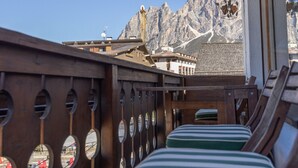 A row of wooden lounge chairs with striped cushions on a balcony overlooking a mountainous landscape. - Casa Cristallino, in the town center with panoramic view (Cortina d´Ampezzo)