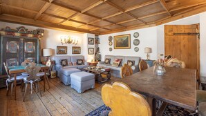 A cozy living room with a wooden ceiling, a sofa set, a dining table, and a decorative cabinet. - Casa Cristallino, in the town center with panoramic view (Cortina d´Ampezzo)