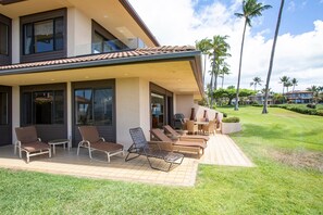 A modern house with a patio area featuring multiple lounge chairs and a dining table. - Makena Surf, #f-104 3 Bedroom Condo (Kihei)
