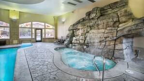 An indoor pool area with a waterfall feature, stone walls, and a view of the outside. - Villa 2082 2 Bed 2 Bath Full Kitchen 2 Bedroom Villa (Midway)