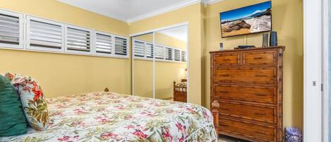 A bedroom with a bed, dresser, and a ceiling fan.