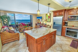 Una cocina amplia con una isla grande, armarios de madera y vista al océano.