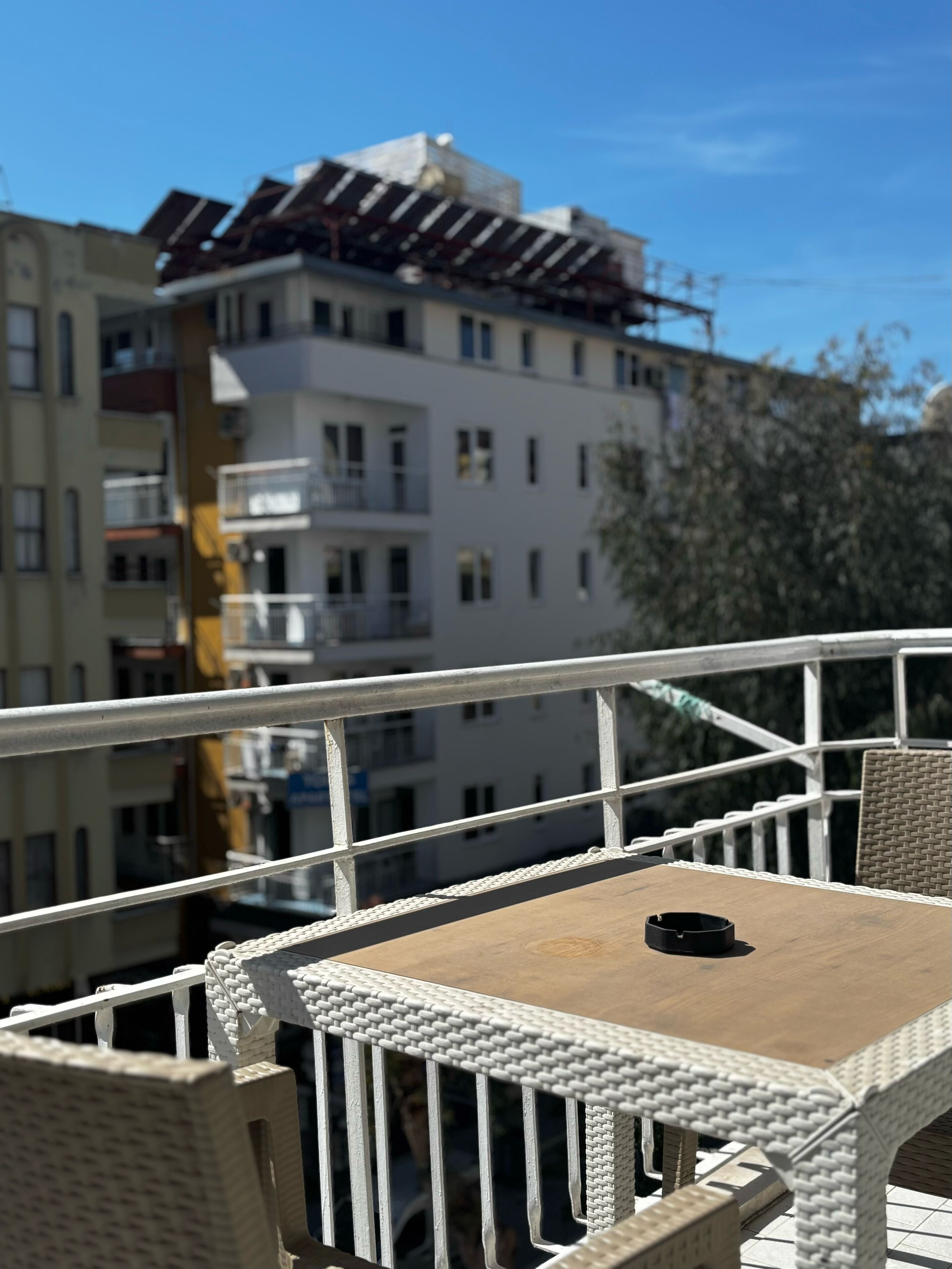 Een balkon met rieten meubels, een tafel en een leuning.