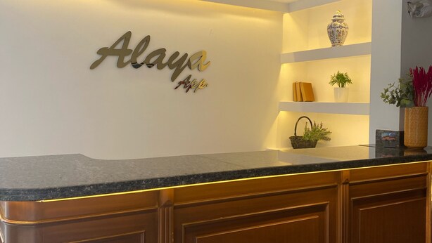 A reception desk with a marble countertop, wooden cabinets, and a wall-mounted sign that reads "Alaya." - Alaya Apart Otel (Alanya)