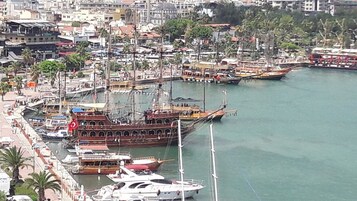 Ein Yachthafen mit verschiedenen vertäuten Booten, darunter ein großes Schiff mit einer roten Flagge.