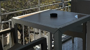 A balcony with a table and chairs, overlooking a residential area with trees and buildings. - Alaya Apart Otel (Alanya)