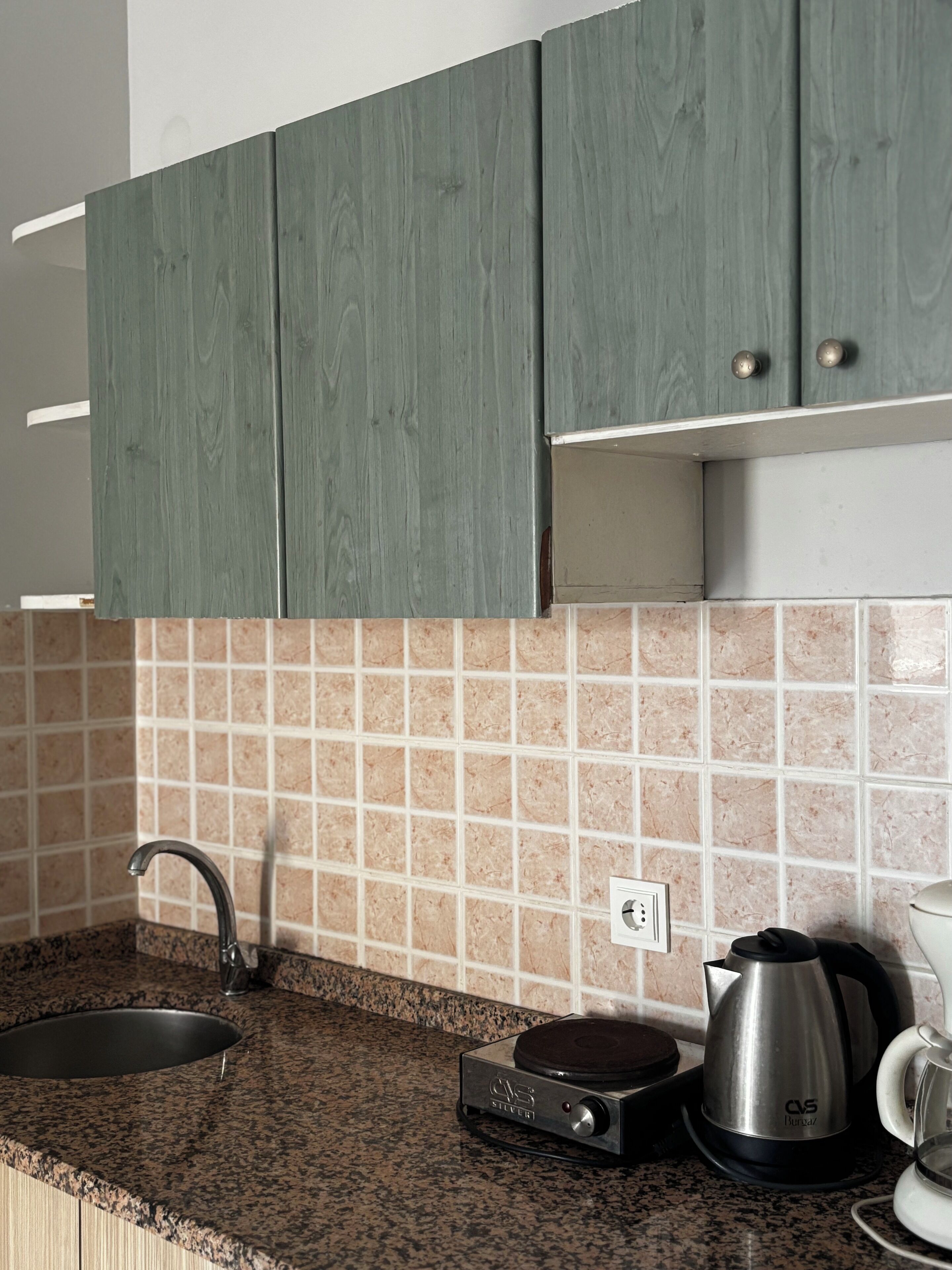 A kitchen with granite countertops, a coffee maker, and a kettle.