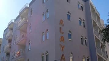 Ein mehrgeschossiges Gebäude mit Balkonen, beschriftet mit „ALAYA“ und „APP.OTEL MiGROS jet“.