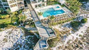 Eine Vogelperspektive zeigt ein Resort mit einem großen Pool, einer Sonnenterrasse und einem Gebäude mit Balkonen.