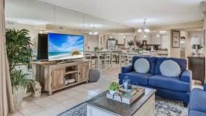 Ein geräumiges Wohnzimmer mit einem großen Flachbildfernseher, einem blauen Sofa und einem Couchtisch.