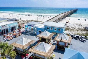A beachside resort with thatched-roof huts, a pier, and a beachfront bar. - Happiness Horizon 2918–Gulf Front–Sleeps 6 (Panama City Beach)