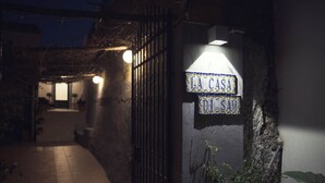 A gated entrance with a sign reading "LA CASA DI SAM" illuminated by a light fixture. - SAM'S HOUSE - A corner of paradise suspended between sky and sea (Amalfi)