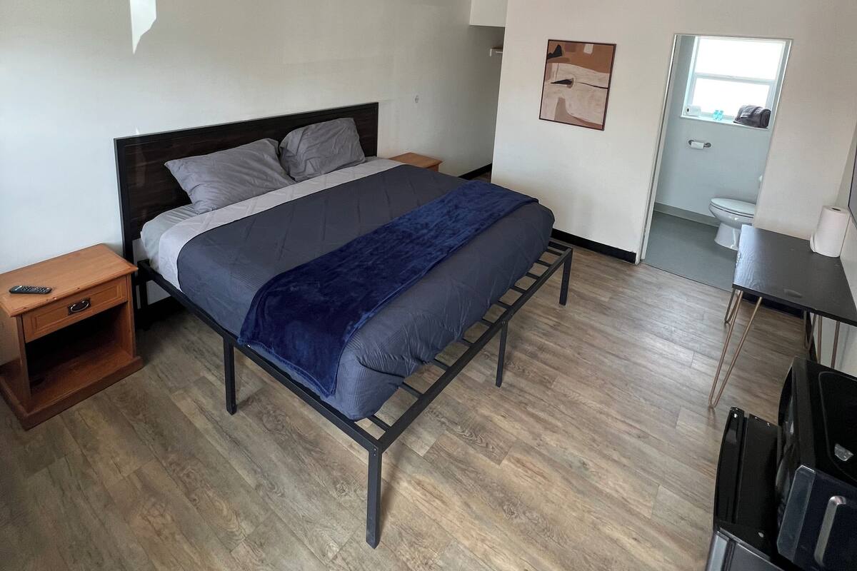 A bedroom with a bed, bedside table, and a small desk with a chair.