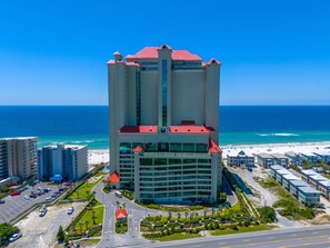 A high-rise hotel with a red roof, located near a beach with a clear blue sky. - Phoenix West 2303 by Liquid Life (Orange Beach)