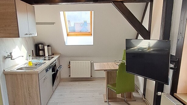 A modern kitchen with a skylight, a dining area, and a television. - Cozy vacation apartment in a historic building (Harztor)