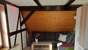 A compact living space with a sloped ceiling, a sofa, a coffee table, and a radiator. - Cozy vacation apartment in a historic building (Harztor)