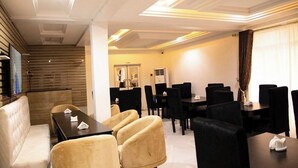 Een hotelconferentieruimte met een modern design, met een combinatie van zwarte en beige stoelen, een centrale tafel en een trap die naar een ander gedeelte leidt.