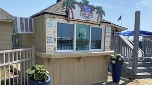 A small outdoor kiosk with a sign reading "Jamaica Moni's" and a menu board listing items like 'Ice Cream' and 'Coconut Cone'.