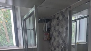 A modern bathroom with a glass shower enclosure, a white sink with a wooden vanity, and a large mirror. - Cozy Caprese house with breathtaking views of the island (Capri)