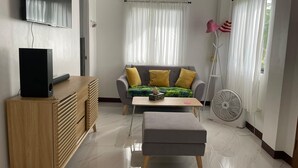 Un salon moderne avec un canapé gris, un meuble en bois et un téléviseur à écran plat.
