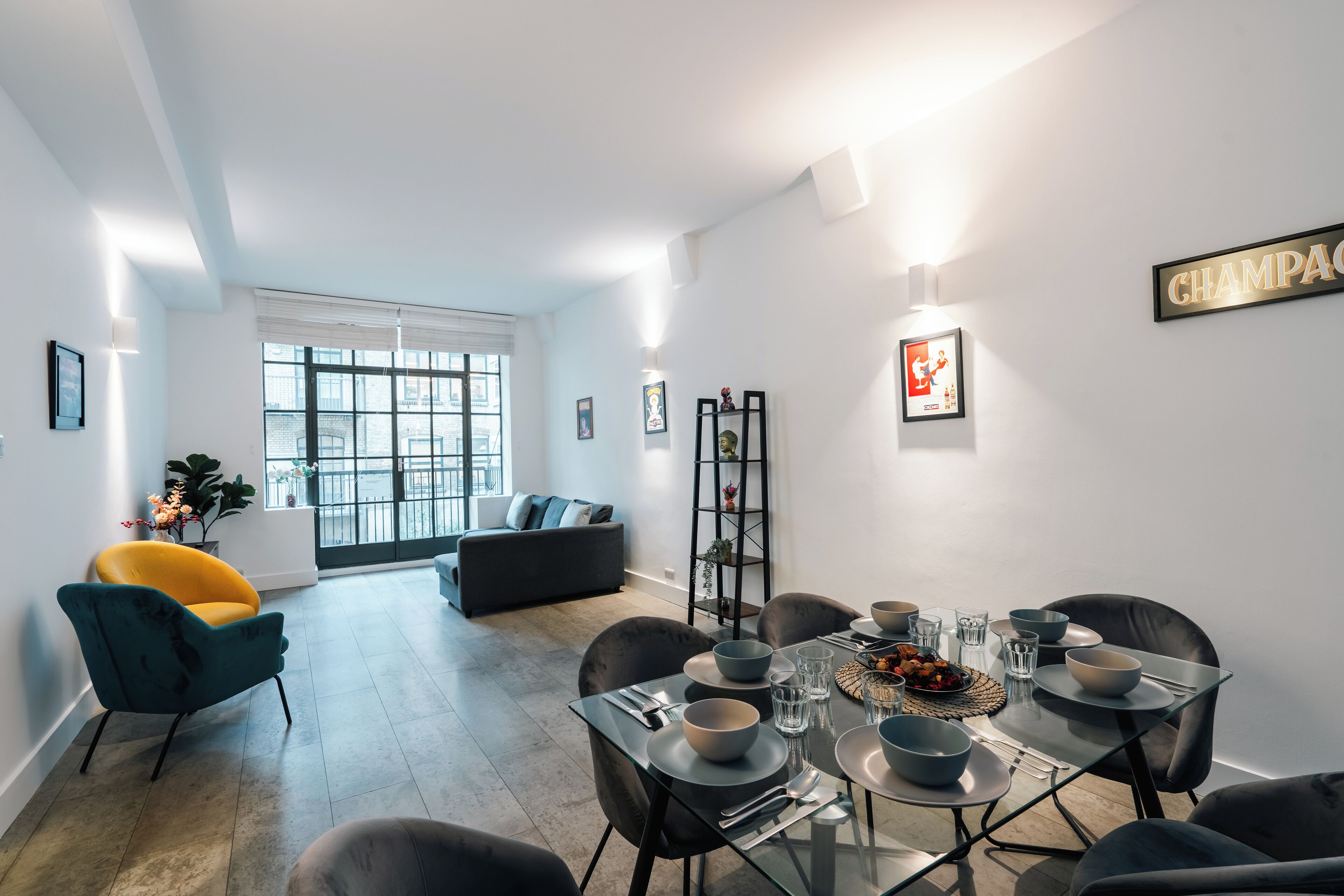 A modern dining area with a glass table, black chairs, and a sofa in the background.