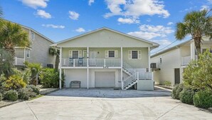 Una casa a due piani con garage antistante, un balcone al secondo piano e un vialetto.
