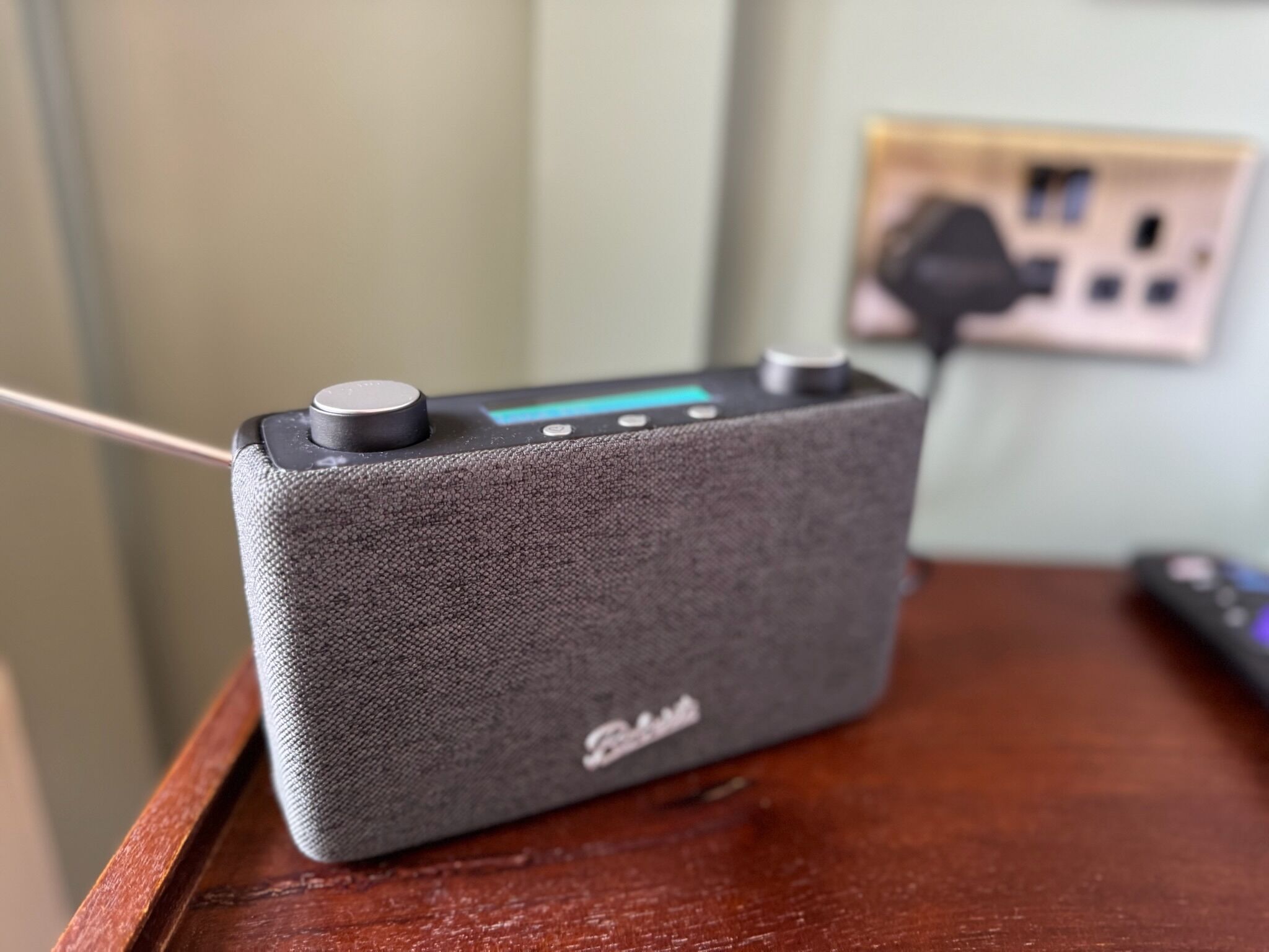 Un haut-parleur portable gris posé sur une surface en bois.