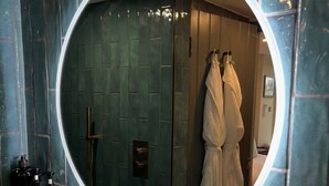A bathroom with a circular mirror, a sink, and toiletries.