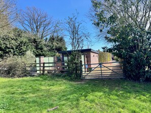 A fenced property with a brick building, a green gate, and a grassy area.
