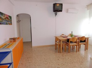 Ein Essbereich mit Tisch, Stühlen und einem an der Wand befestigten Fernseher.