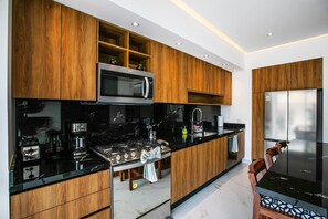 Una cocina moderna con armarios de madera, un microondas integrado, una estufa a gas y un refrigerador de acero inoxidable.