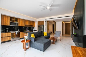 Una sala moderna con un sofá seccional gris, una mesa de centro de madera y un televisor montado en la pared.