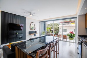 Una cocina moderna con una isla central, un televisor de pantalla plana montado en la pared y un comedor con sillas y una mesa.
