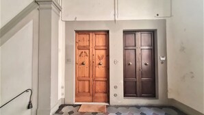A hallway with two wooden doors, a tiled floor, and a small rug at the entrance. - ELEGANT APARTMENT IN THE HEART OF FLORENCE, PIAZZA SIGNORIA (Firenze)