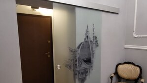 A room with a herringbone wooden floor, a sliding door with a cityscape mural, and a vintage chair. - ELEGANT APARTMENT IN THE HEART OF FLORENCE, PIAZZA SIGNORIA (Firenze)