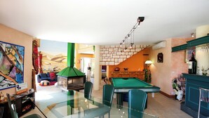 A spacious living area with a pool table, a glass dining table, and a green sofa. - Villa sleeps 14 with heated pool pets welcome (Issel)