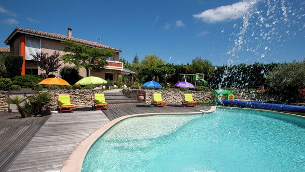 A swimming pool with a wooden deck, surrounded by lounge chairs and umbrellas. - Villa sleeps 14 with heated pool pets welcome (Issel)