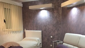 A bedroom with two beds, a small round table, and a modern design with a marble-like wall. - Villa sleeps 14 with heated pool pets welcome (Issel)
