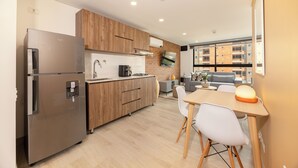 A modern kitchen with a refrigerator, wooden cabinets, and a dining area with a table and chairs.