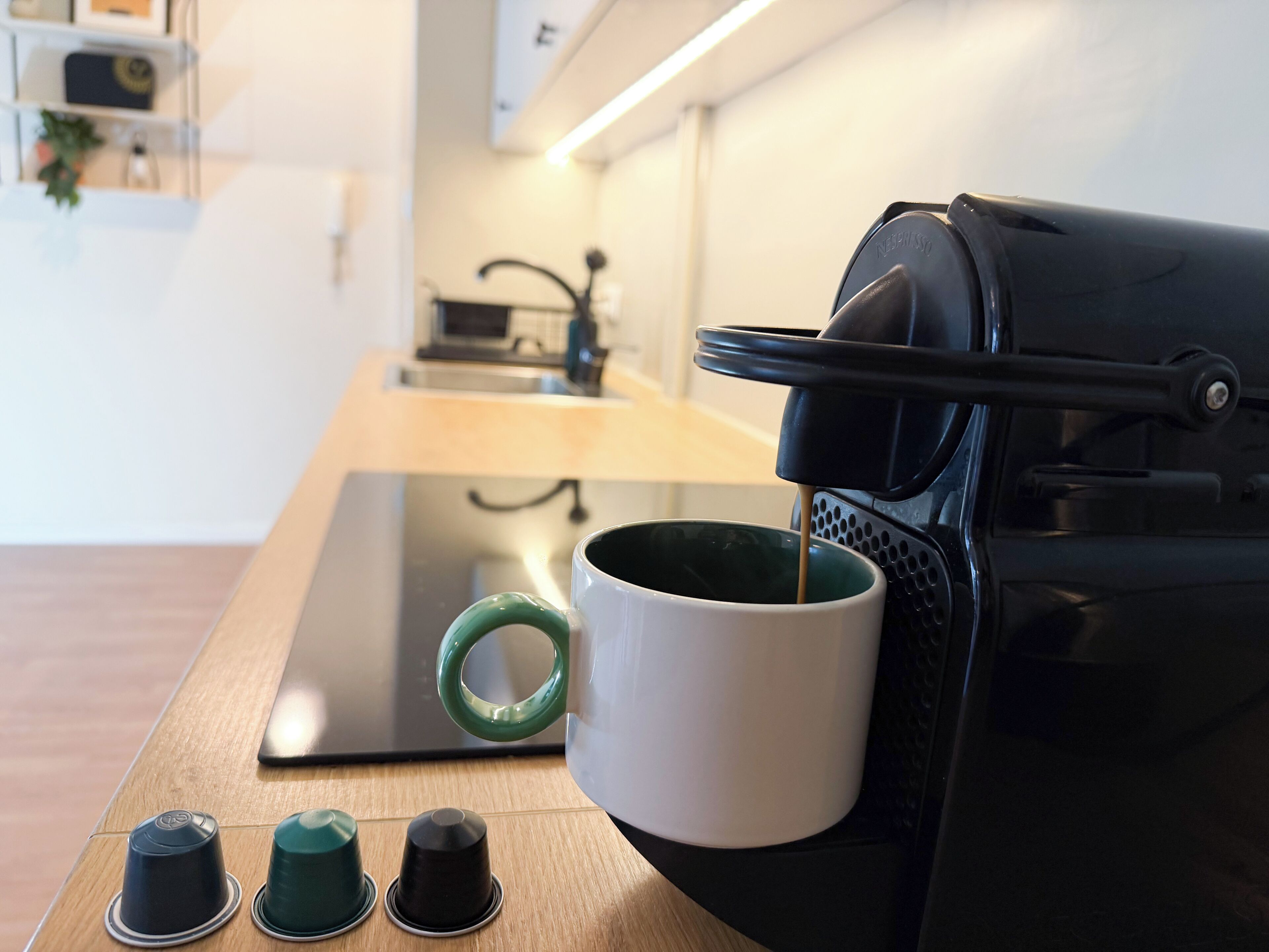 A coffee machine with a cup of coffee, a kettle, and a stovetop.