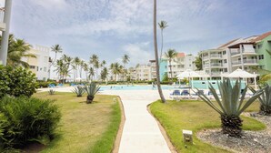 A resort with a swimming pool, palm trees, and multiple buildings with balconies. - Playa Turquesa D403_80Mbps_Private Beach Access_Pools (Bavaro-Punta Cana)