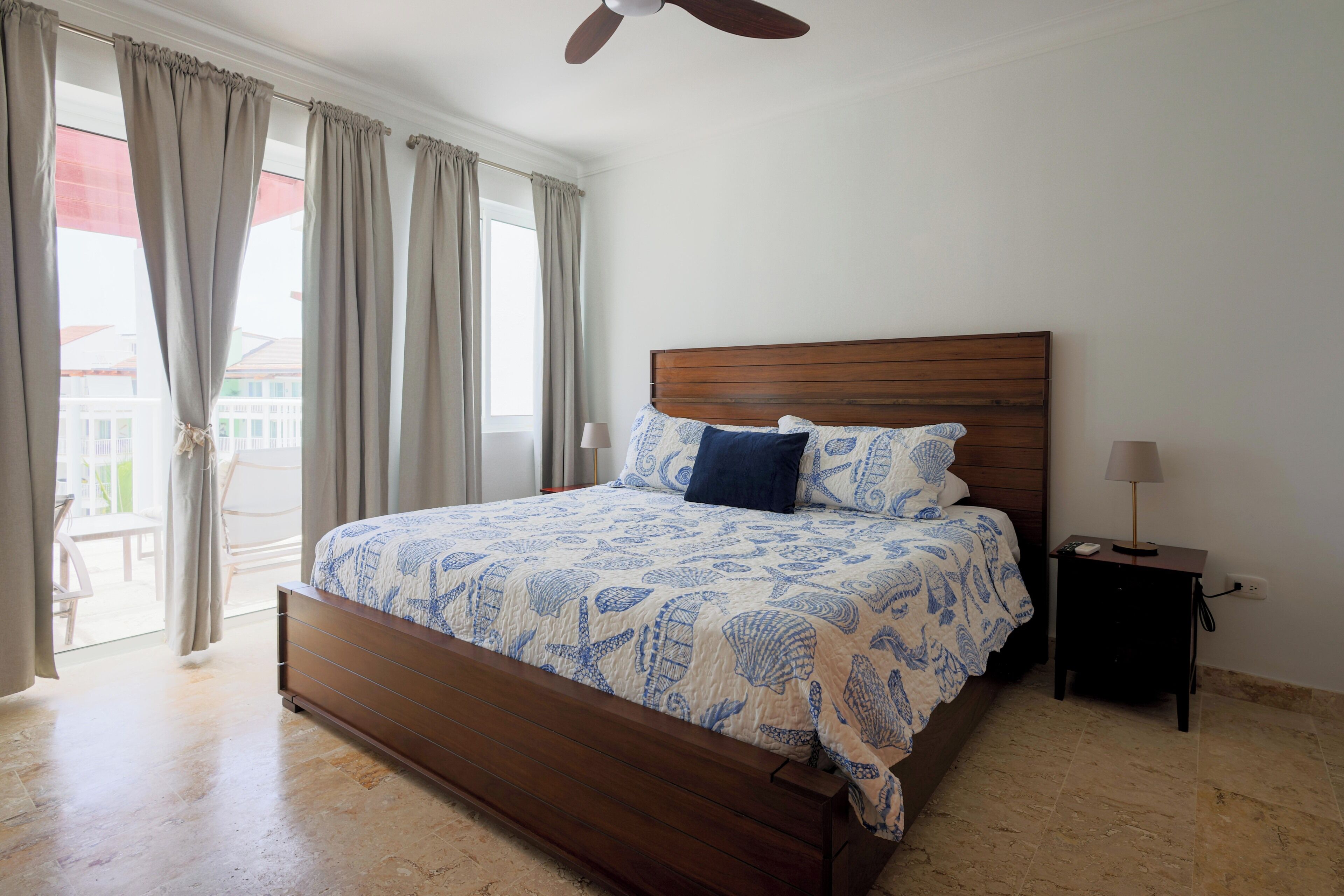 A bedroom with a wooden bed, a nightstand, a lamp, and a ceiling fan.