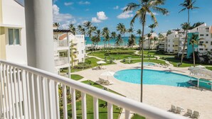 A resort with a pool, palm trees, and beachfront views. - Playa Turquesa D403LO_80Mbps_Private Beach Access_Pools (Bavaro-Punta Cana)