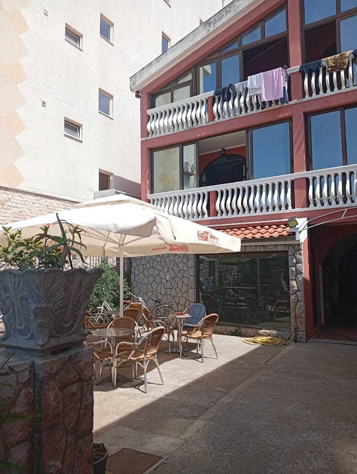 A building with a two-story balcony, outdoor seating with umbrellas, and a Coca-Cola sign.