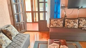 Un salon avec un canapé, une table basse et un téléviseur.