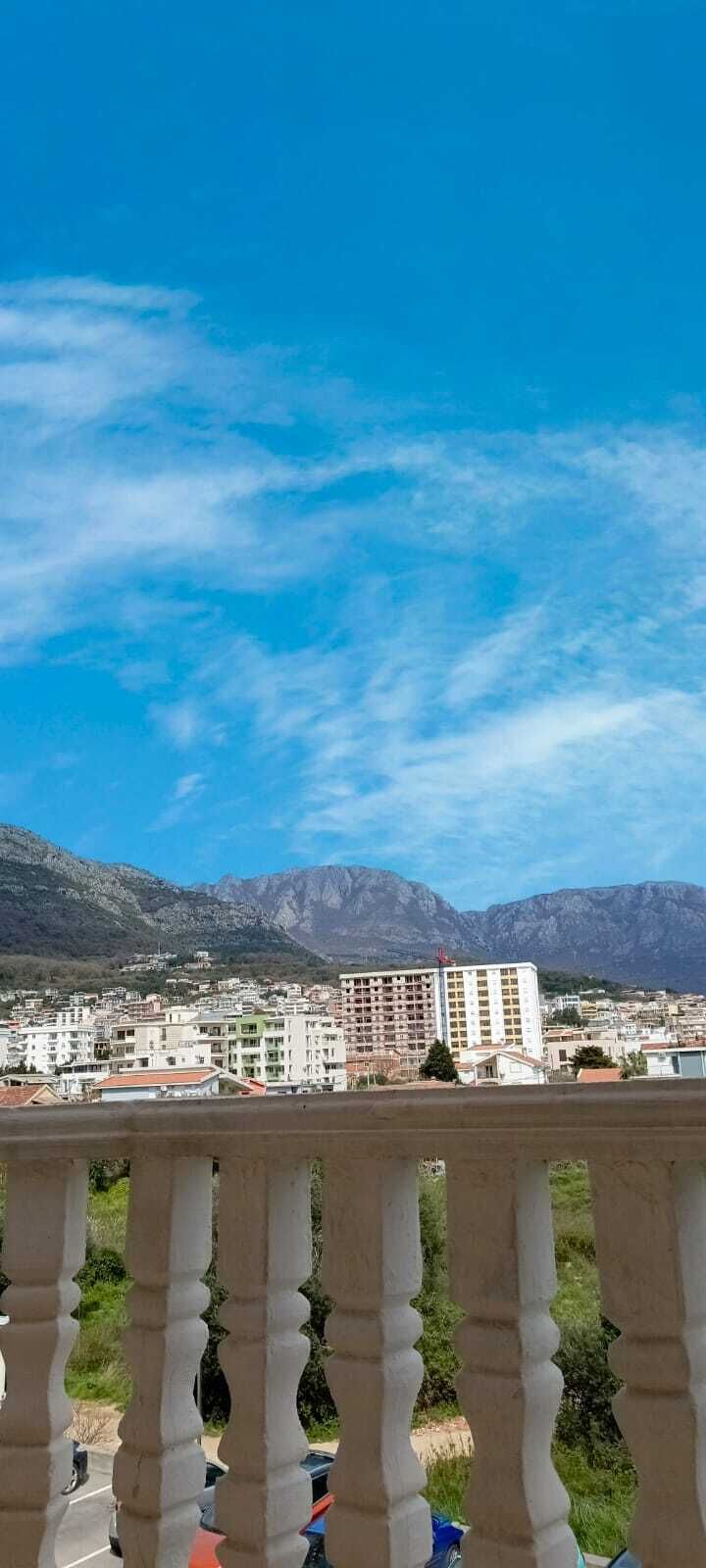 Un balcón con vistas a un paisaje urbano y montañas.