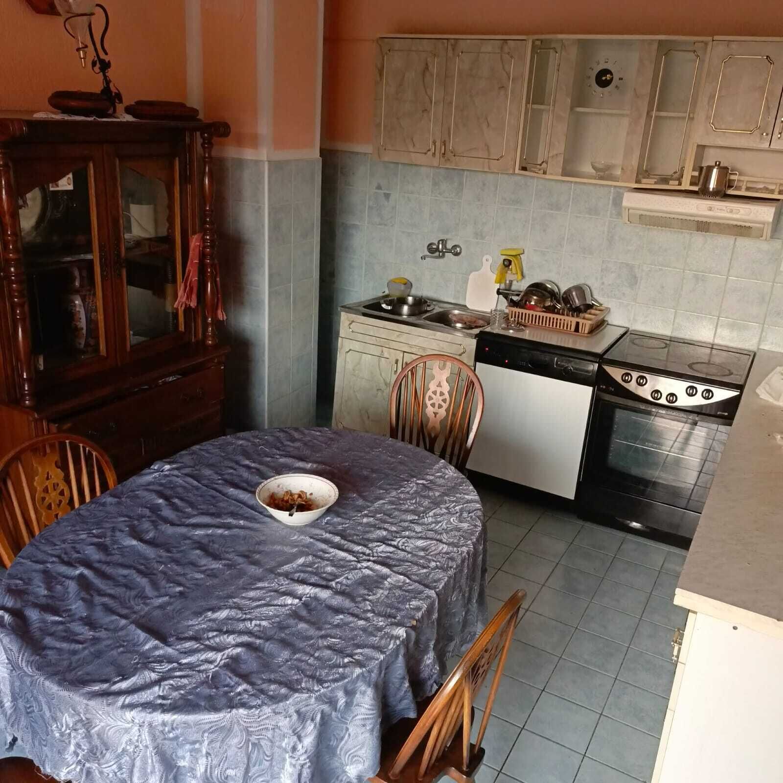 Una cocina compacta con mesa, sillas, estufa y lavamanos.